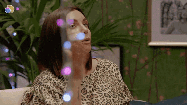 a woman in a leopard print shirt is sitting in front of a picture