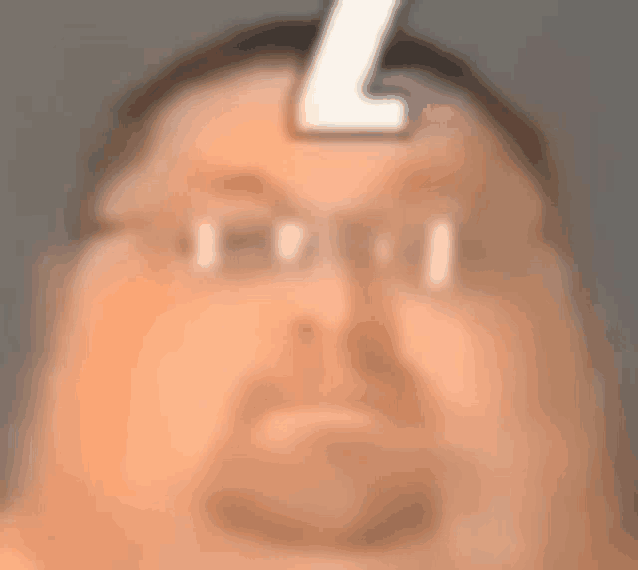 a close up of a man 's face with glasses and a letter l on his forehead .