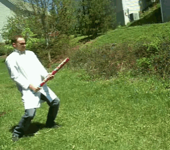 a man in a lab coat is holding a bat in a grassy field