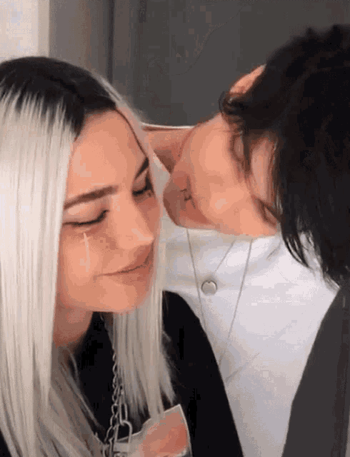 a man and a woman are kissing and the woman has a cross in her eye .