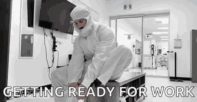 a man in a clean room is kneeling down on a table and getting ready for work .
