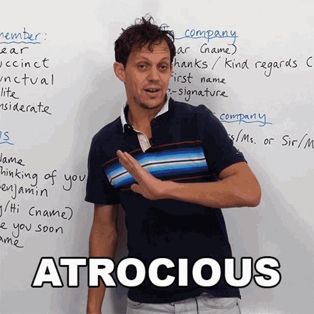 a man is standing in front of a white board with the word atrocious on it