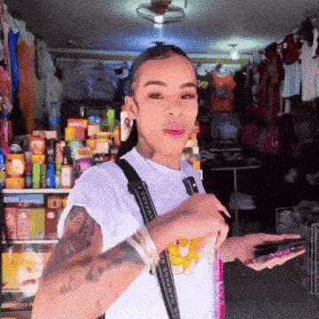 a woman with a tattoo on her arm is holding a cell phone in front of a store .