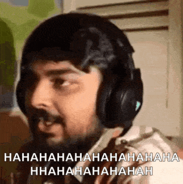 a man with a beard wearing headphones is laughing and making a funny face .