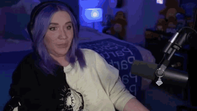 a woman with purple hair is sitting in front of a microphone wearing headphones .