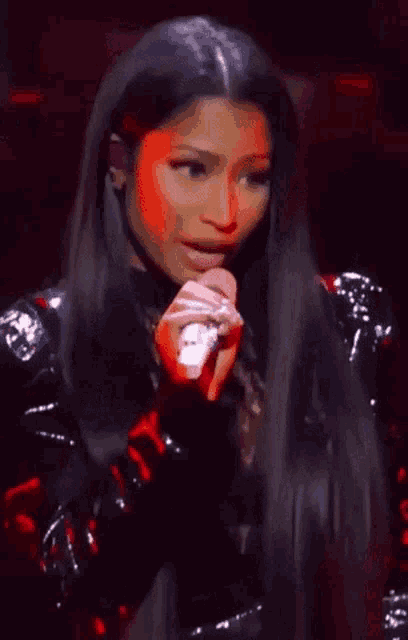 a woman with long hair is singing into a microphone on a stage