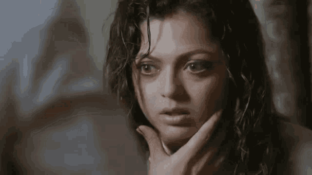 a woman with a hand on her face looks at the camera
