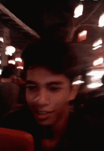 a blurry picture of a person holding a cell phone in a crowded room .