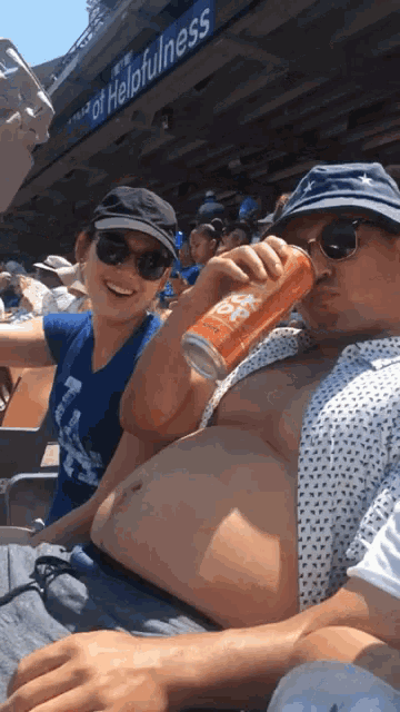 a man and a woman are drinking beer in front of a sign that says helpfulness