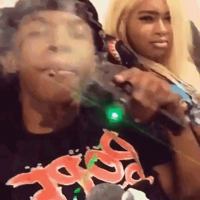 a man and a woman are smoking a cigarette and holding guns .