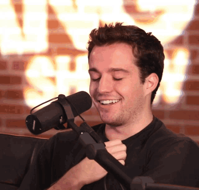 a man wearing headphones and a shure microphone smiles