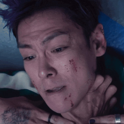 a close up of a man 's face with a tattoo on his arm