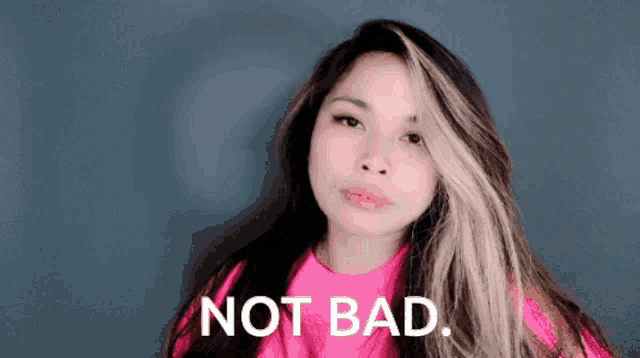 a woman in a pink shirt says not bad in front of a blue background