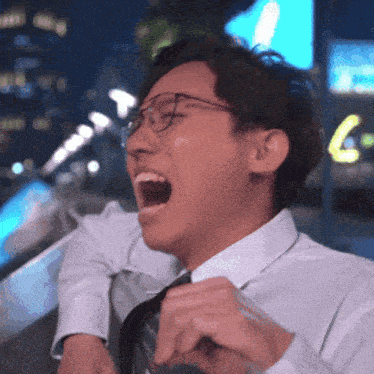 a man in a white shirt and tie is laughing with his mouth open