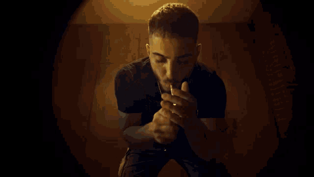 a man in a black shirt is looking at a cell phone in a dark room .