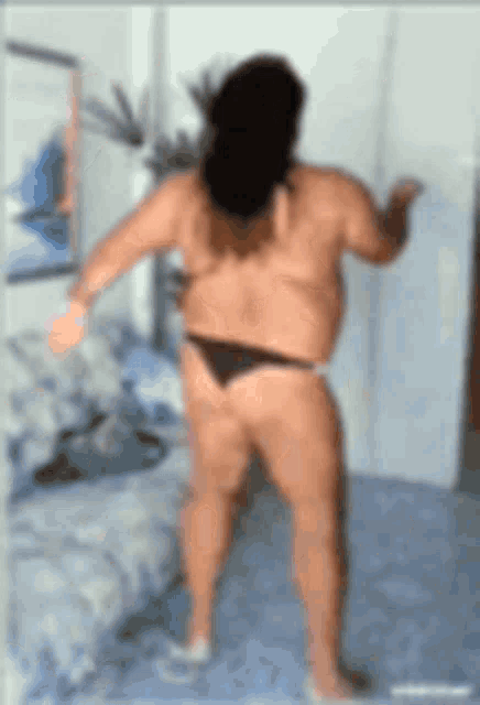 a naked man in a bikini is standing in a room .