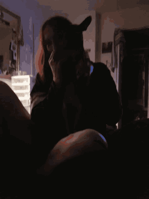 a woman with red hair is sitting in a dark room with a dog