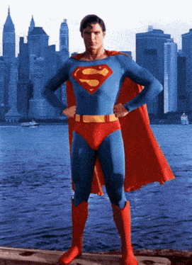 a man in a superman costume stands in front of a city skyline with his hands on his hips