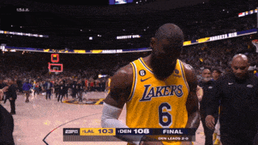 a basketball player wearing a lakers jersey is walking off the court