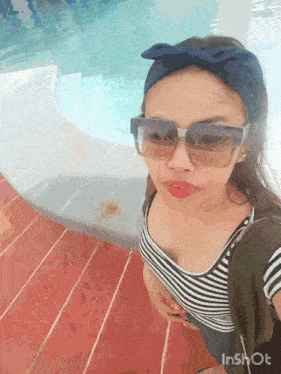 a woman wearing sunglasses and a headband is standing in front of a pool