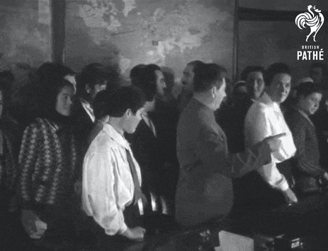 a group of people are gathered in a room with the word pathe on the bottom right
