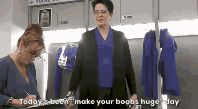a woman is standing in a locker room talking to another woman who is writing on a piece of paper .