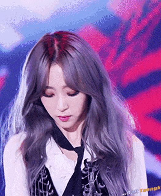 a woman with long gray hair is wearing a tie and looking down .
