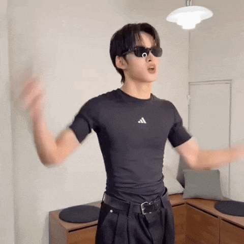a man wearing sunglasses and a black shirt is dancing in a room .