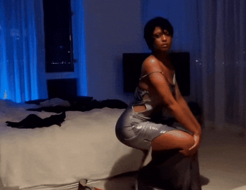 a woman in a silver dress is sitting on a bed
