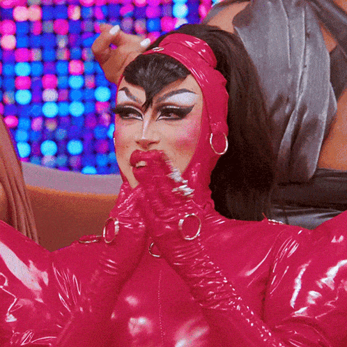 a drag queen wearing a pink latex outfit with a headband and gloves