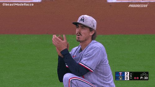 a baseball player wearing a hat with the letter m on it is clapping
