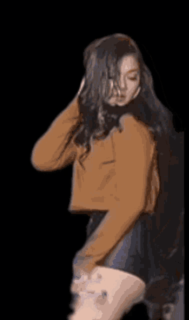 a woman in a brown sweater and black shorts is dancing .