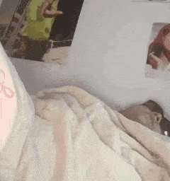 a person is laying in bed with a blanket and a tattoo on their arm .