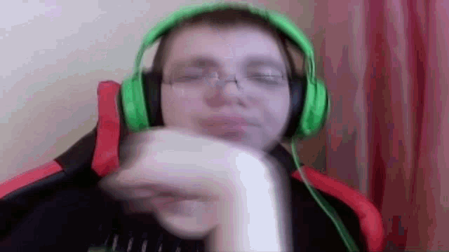 a man wearing green headphones and glasses is sitting in a chair .