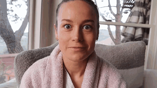 a woman wearing a pink towel around her neck looks surprised