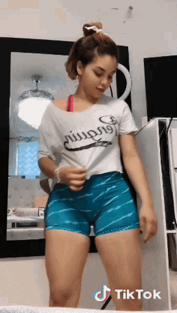 a woman wearing shorts and a t-shirt that says ' tiktok ' on it