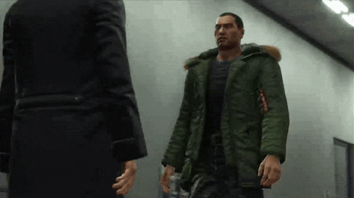 a man in a green parka is talking to another man in a suit .