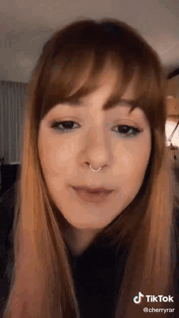 a close up of a woman 's face with a nose ring on it .
