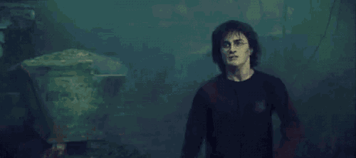 harry potter is holding a sword in his hand in a dark room .