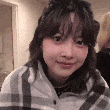 a young woman wearing a plaid shirt is smiling for the camera .