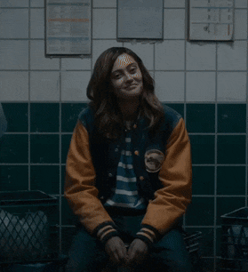a woman with a bandage on her forehead is wearing a varsity jacket