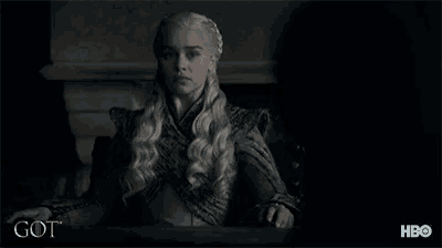 a woman is sitting at a table with the word got on the bottom right