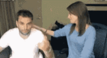 a woman in a blue sweater is putting her hand on a man 's back .