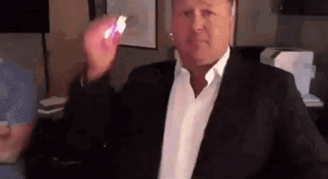 a man in a suit and white shirt is holding a lighter in his hand .