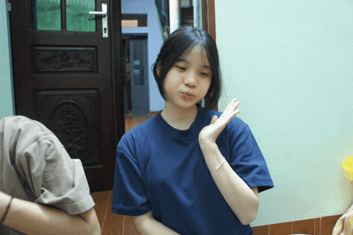 a girl wearing a blue shirt making a funny face