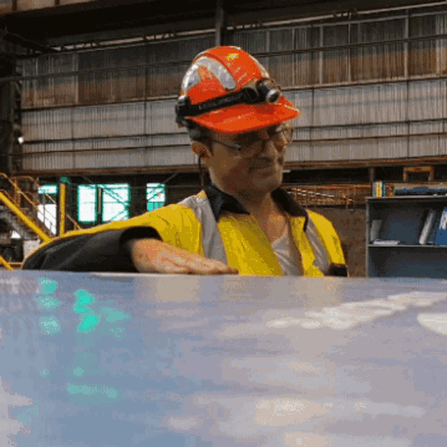 a man wearing a hard hat and safety vest is sitting at a desk