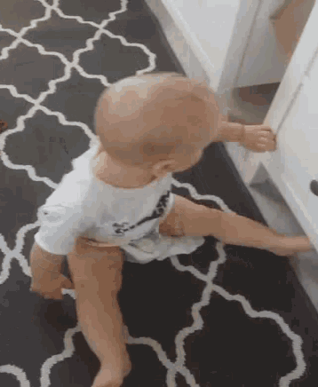 a baby in a diaper is crawling on a rug .