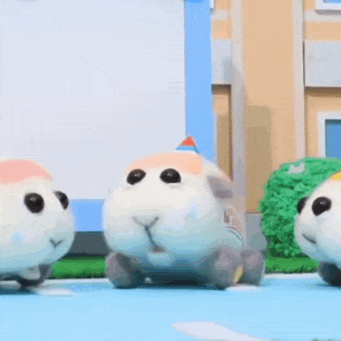 a couple of stuffed animals are standing next to each other on a table .