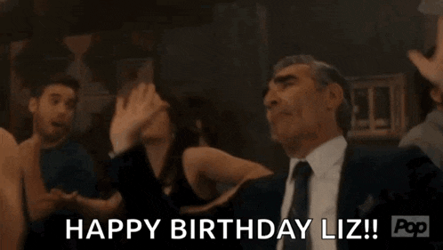 a man in a suit and tie is celebrating his birthday with his hands in the air .