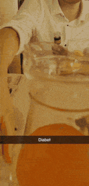 a man sitting at a table with a bottle of alcohol and a pitcher of orange juice that says diabel
